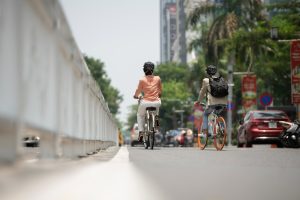 Cena de mobilidade urbana no Brasil mostrando duas pessoas indo ao trabalho de bicicleta em uma rua da cidade, destacando sustentabilidade, saúde e mudanças nos hábitos de deslocamento. A imagem reflete tendências atuais que influenciam a qualidade de vida nas cidades brasileiras, enfatizando a infraestrutura cicloviária, a redução do congestionamento e o papel da mobilidade ativa no estilo de vida urbano contemporâneo e na atualidade.