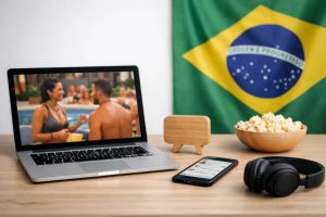 Notebook exibindo cena de reality show brasileiro em uma mesa com smartphone, fones de ouvido e pipoca, ao fundo a bandeira do Brasil, representando o papel do entretenimento e dos reality shows no Brasil e como eles continuam dominando conversas online e redes sociais.